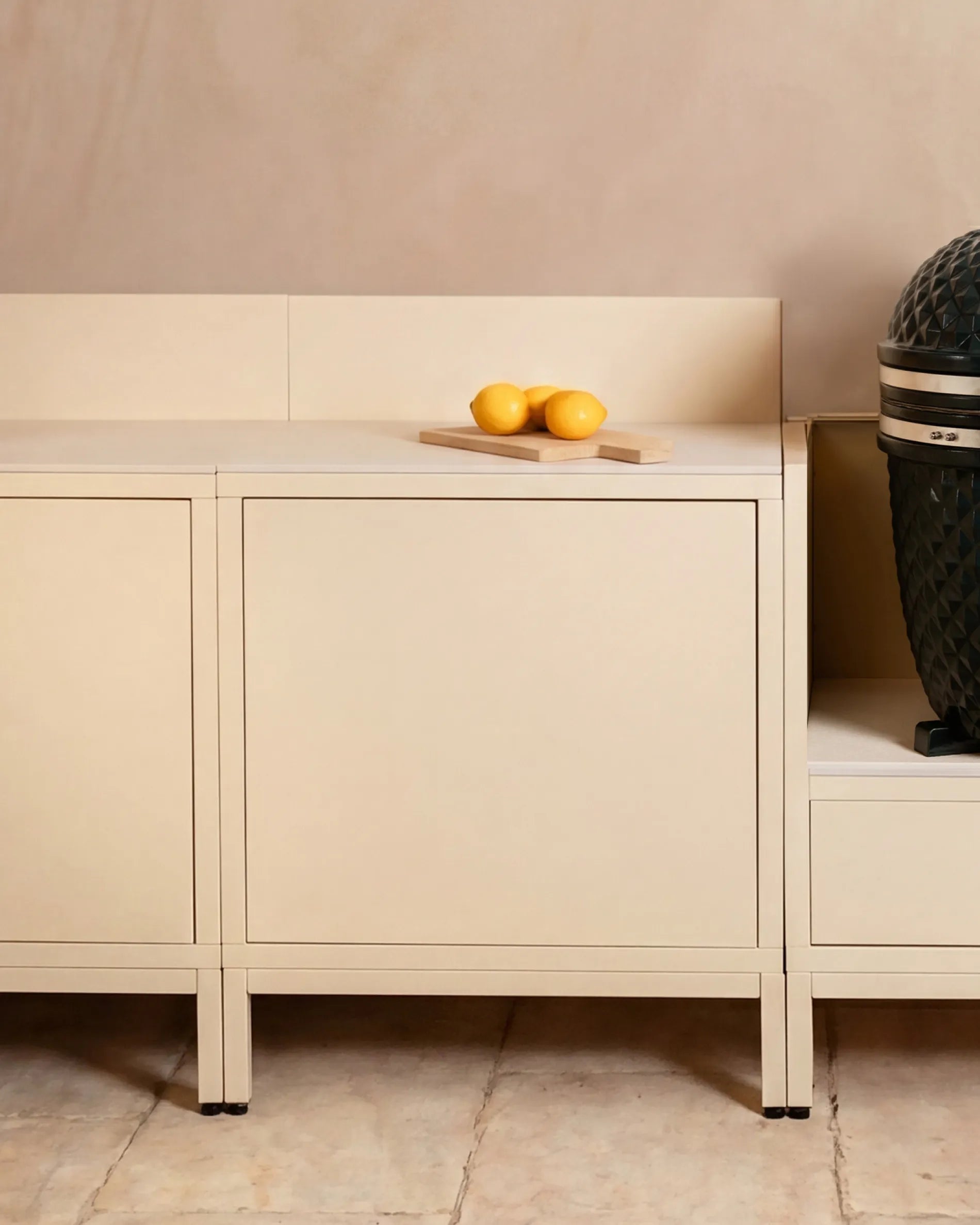 Crèmekleurige Classic PILOTIS modulekasten voor buitenkeukens, met kamado en citroenen op het werkblad