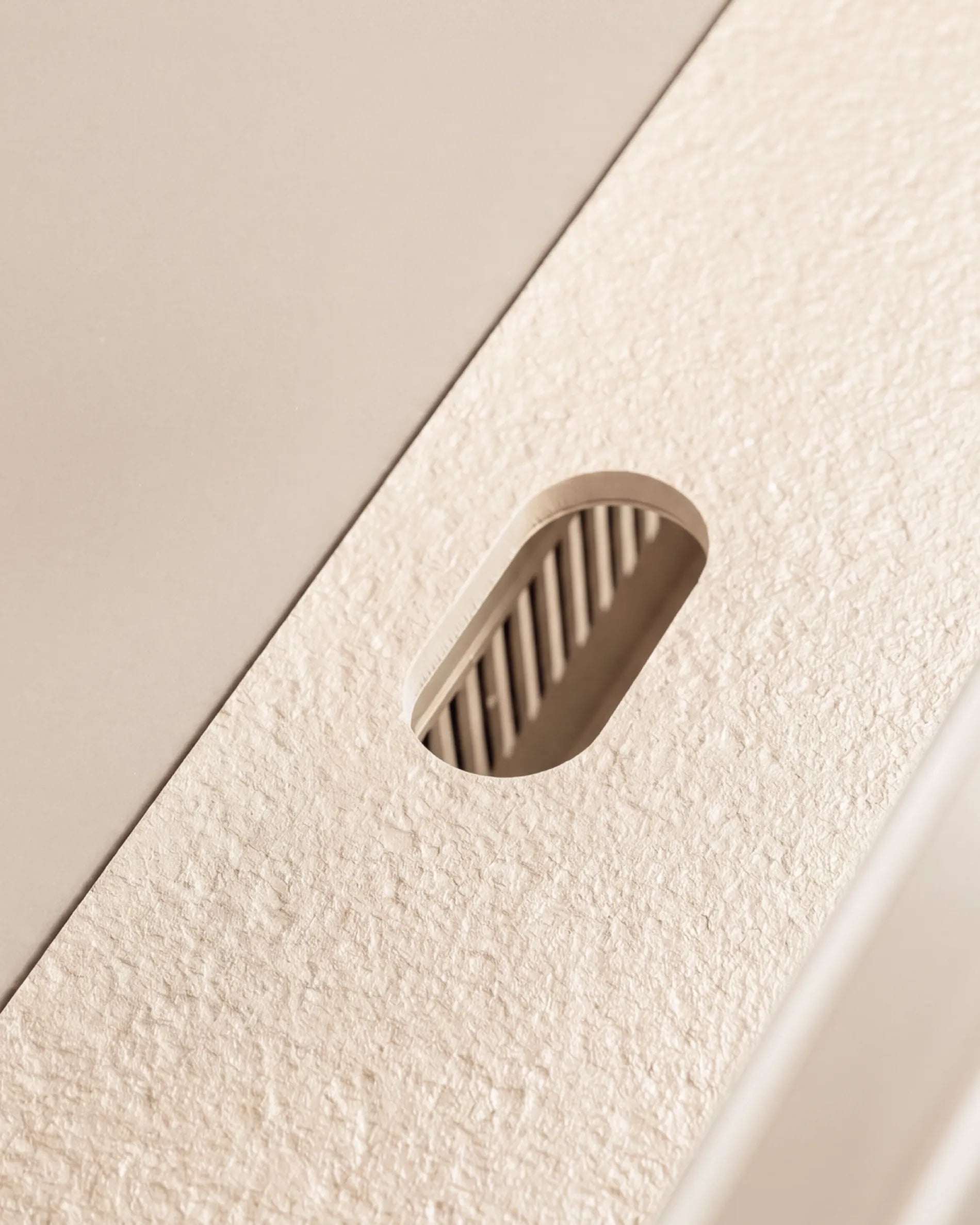 Ovale uitsnede van het beige-crèmekleurige blad van de Plancha PILOTIS-module, close-up van de granietachtige textuur