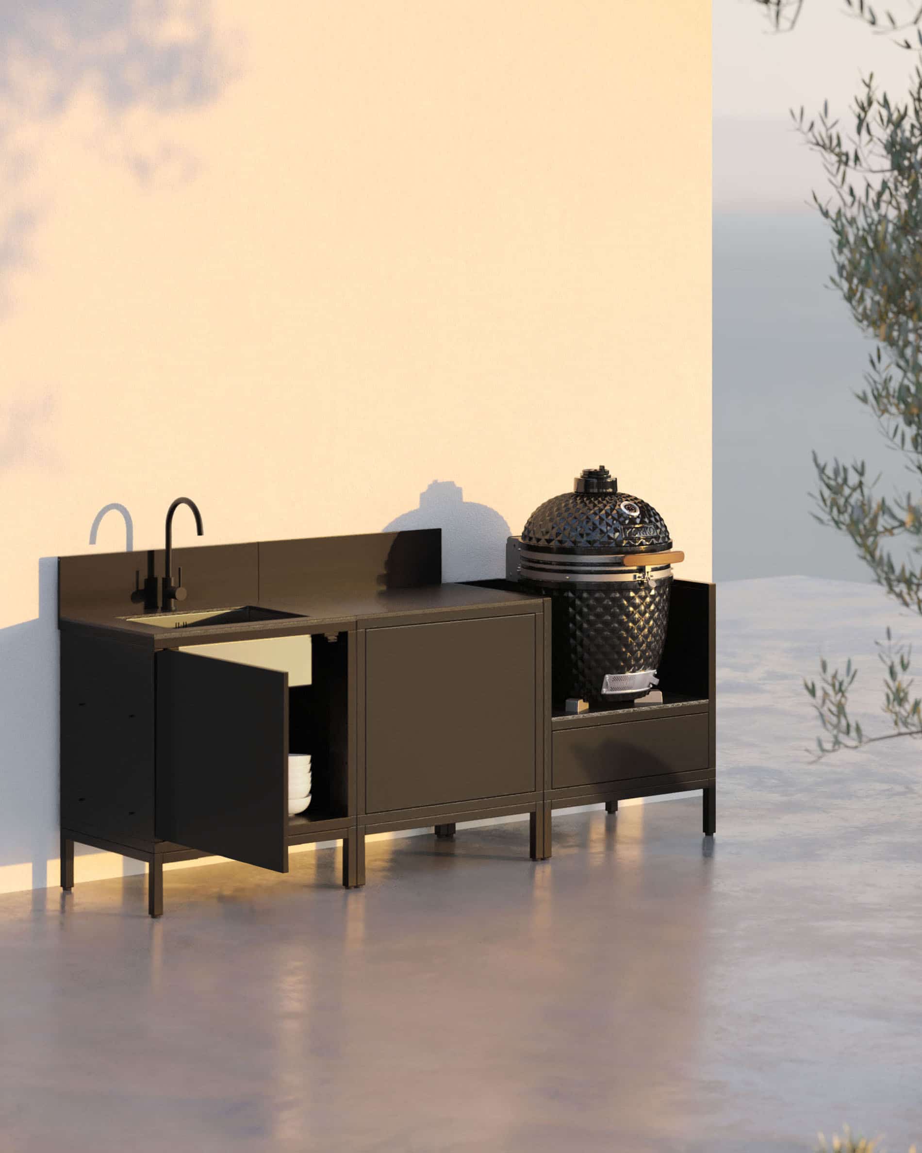 Cuisine pilotis 3 modules pour kamado avec évier intégré, meuble coloris noir avec plan de travail et crédence assortis, évier avec robinet à gauche, module central de rangement fermé et kamado intégré dans le module latéral droit, structure sur pieds noirs, installation en extérieur.