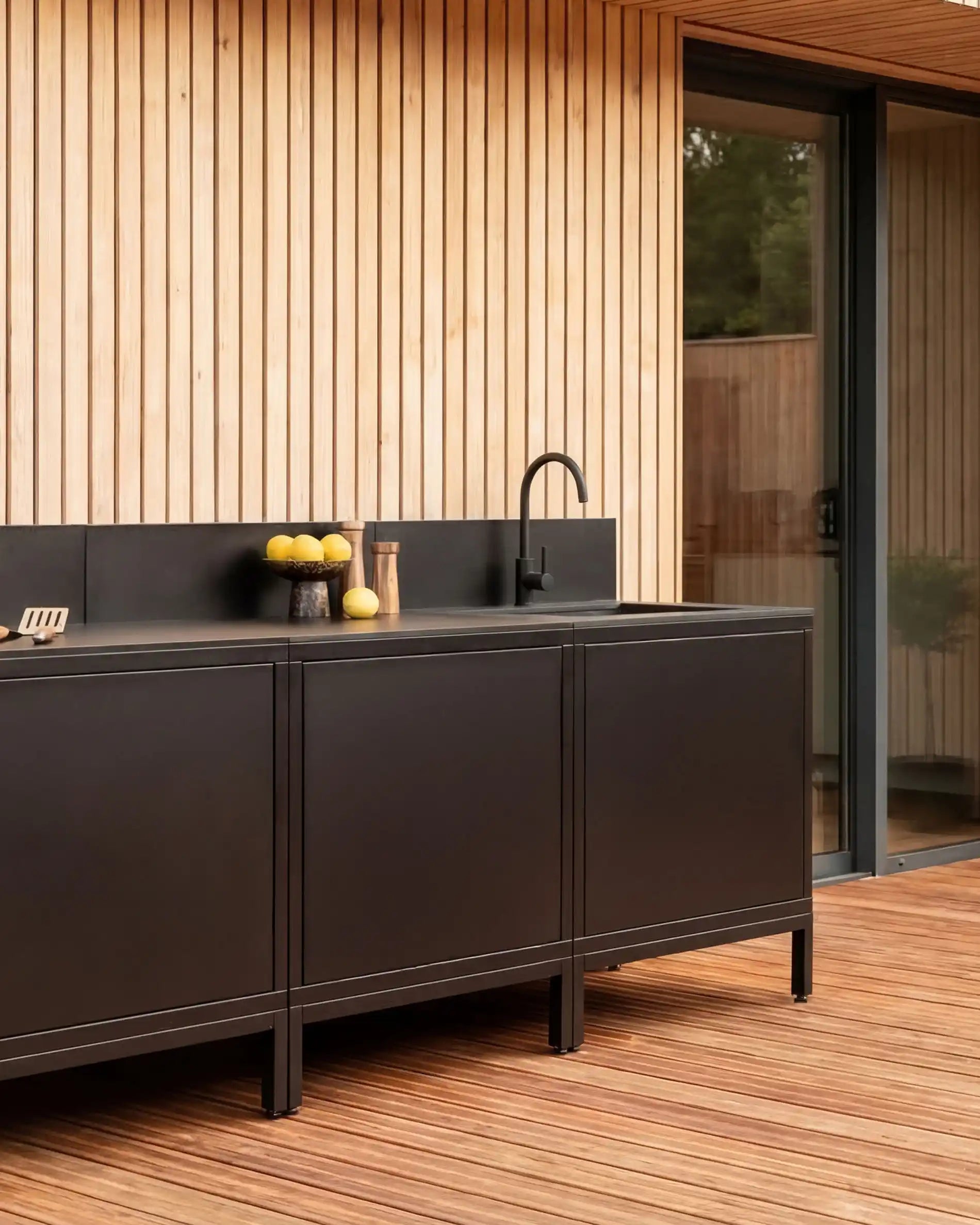 Kokko buitenkeuken in zwart design met werkblad en decoraties.