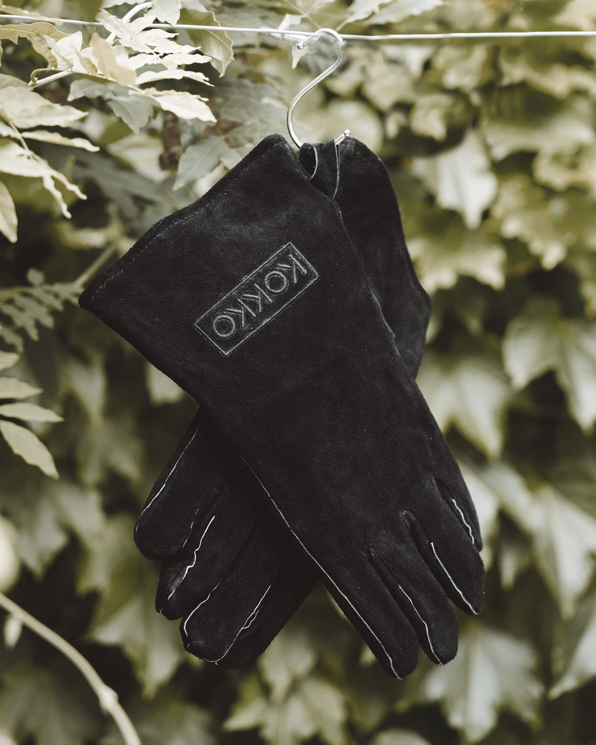 Gants en cuir Kokko noirs suspendus, conçus pour la manipulation du kamado et des accessoires de cuisson.