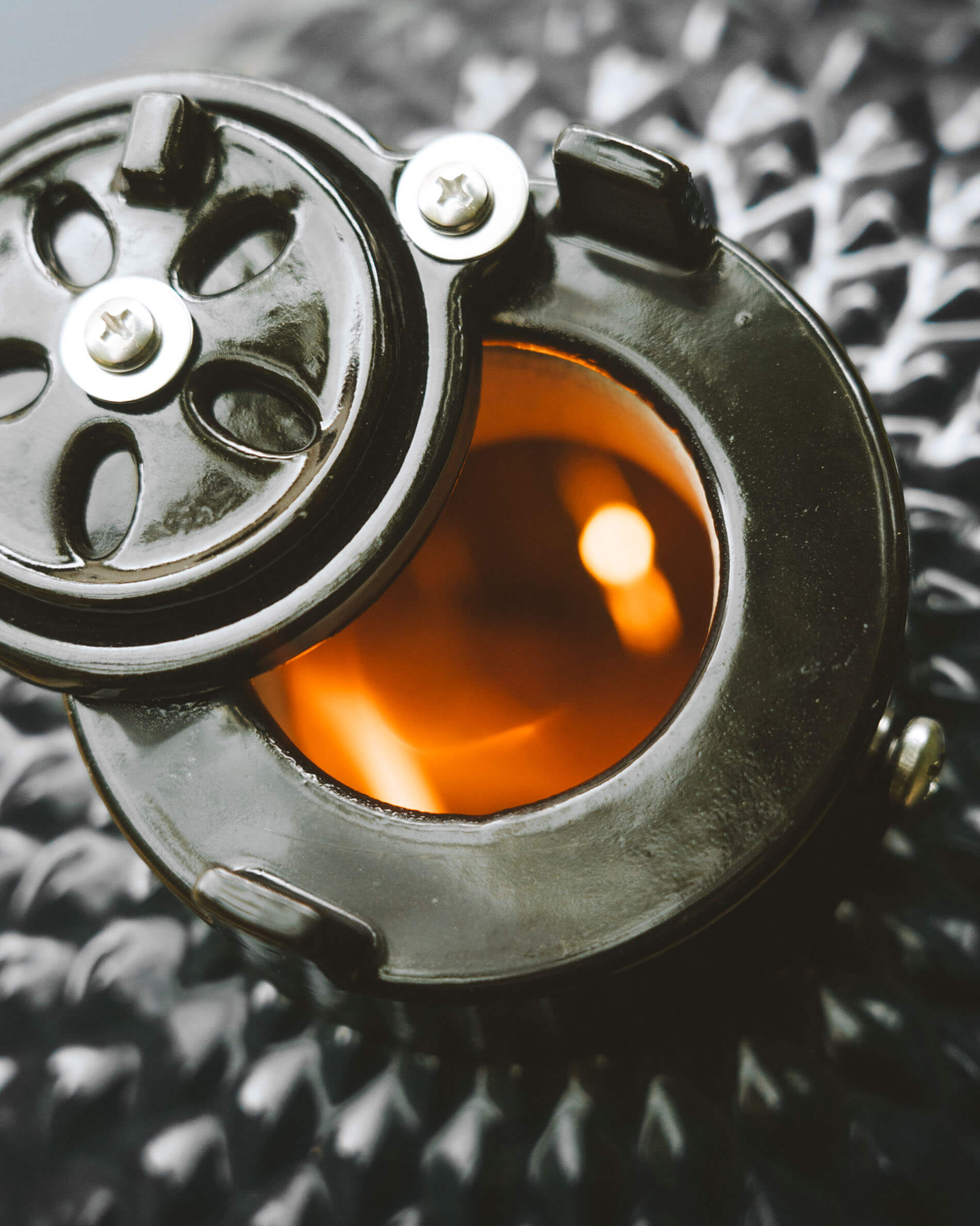 Close-up van het bovenste ventilatiesysteem van een Kokko kamado, met ronde opening en zichtbaar gloeiend vuur.