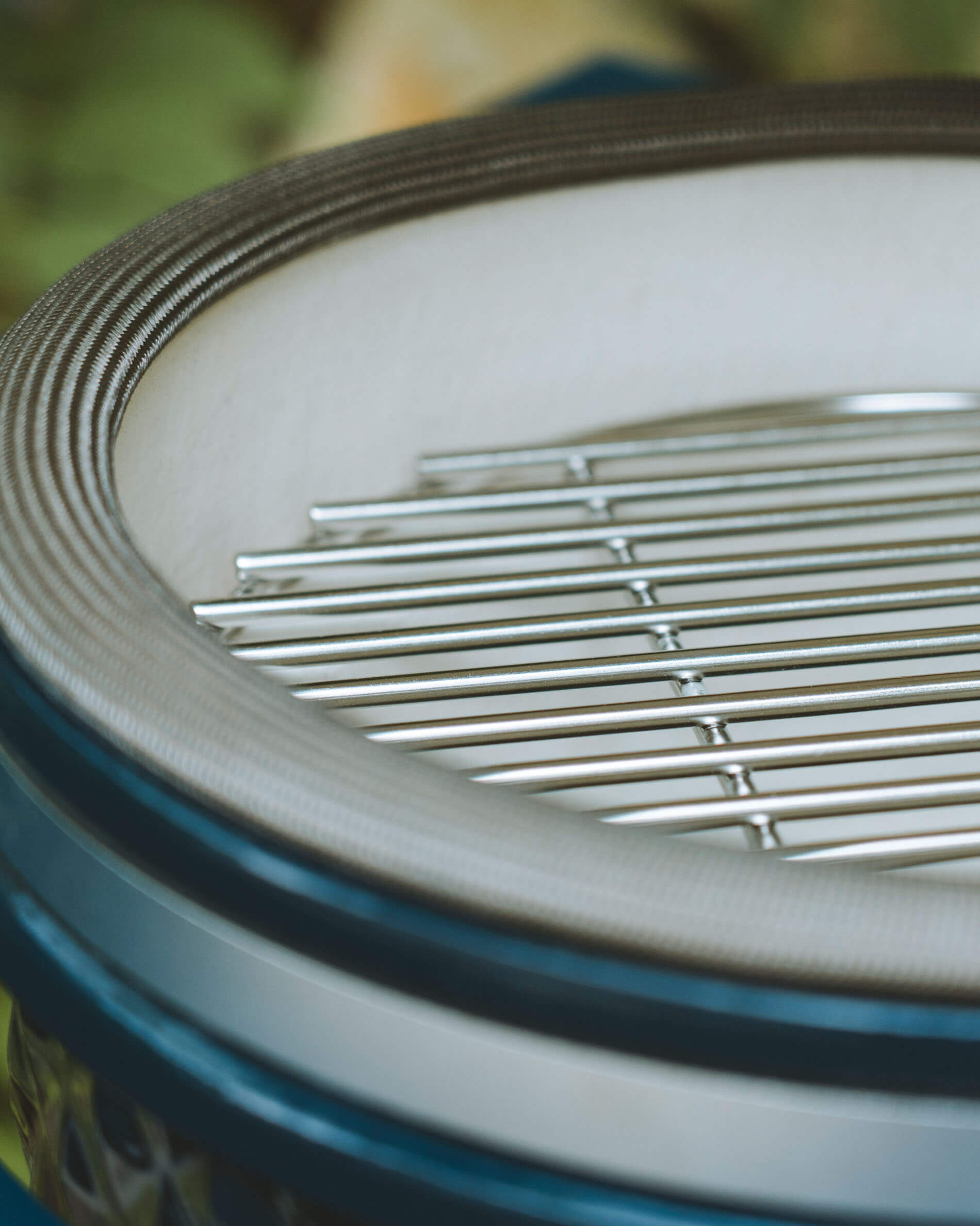 Close-up van het roestvrijstalen grillrooster en de dekseldichting van een Kokko kamado in oceaankleur.