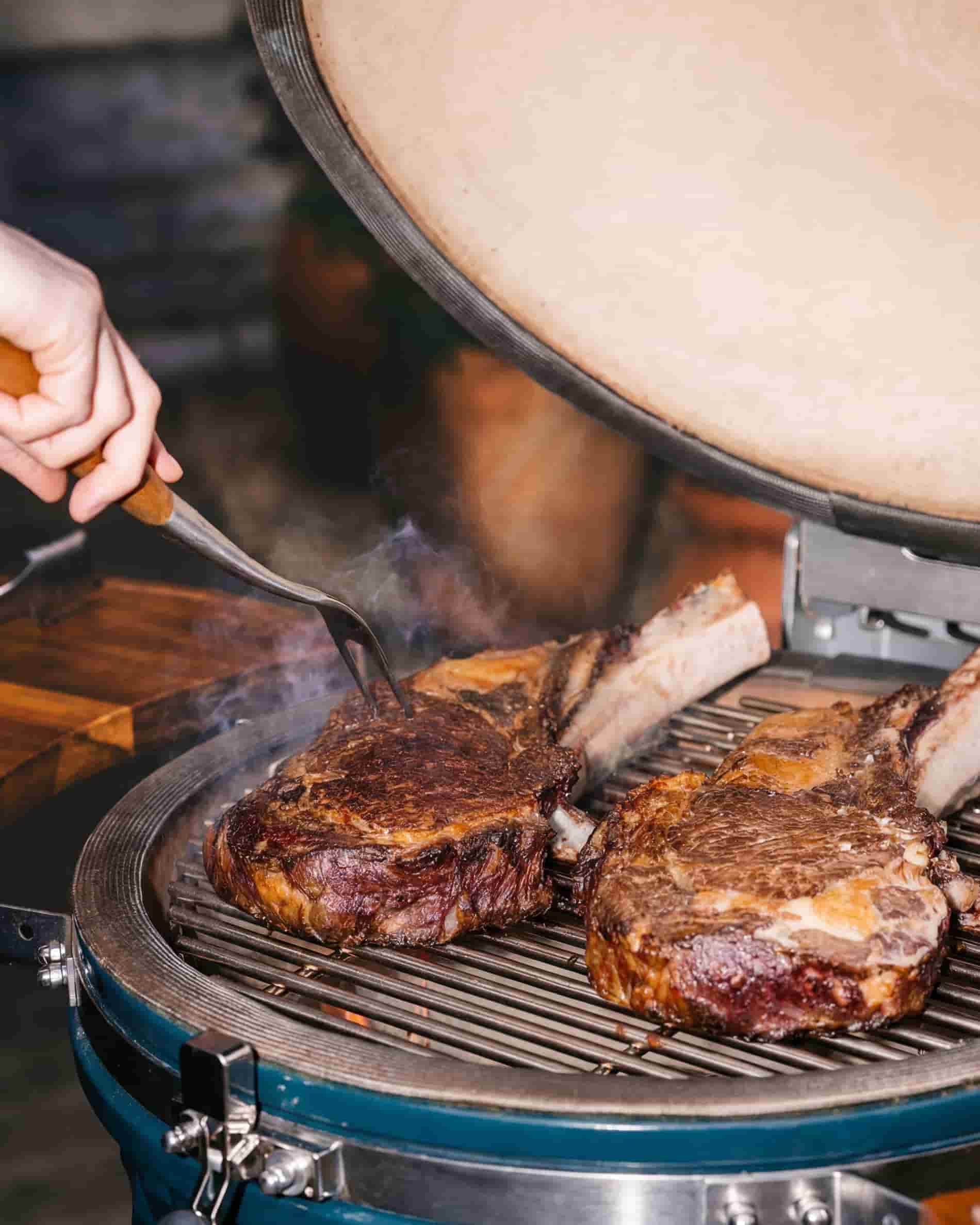 Vleesbereiding op het rooster van een Kokko XL 22 inch kamado, met open deksel.
