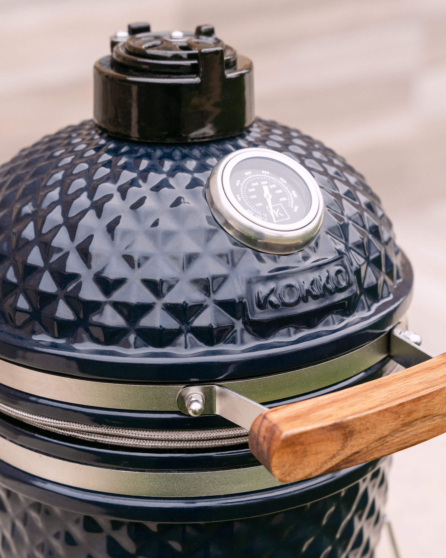 Kamado Little Kokko 13 van keramiek in marineblauw met houten zijtafel.