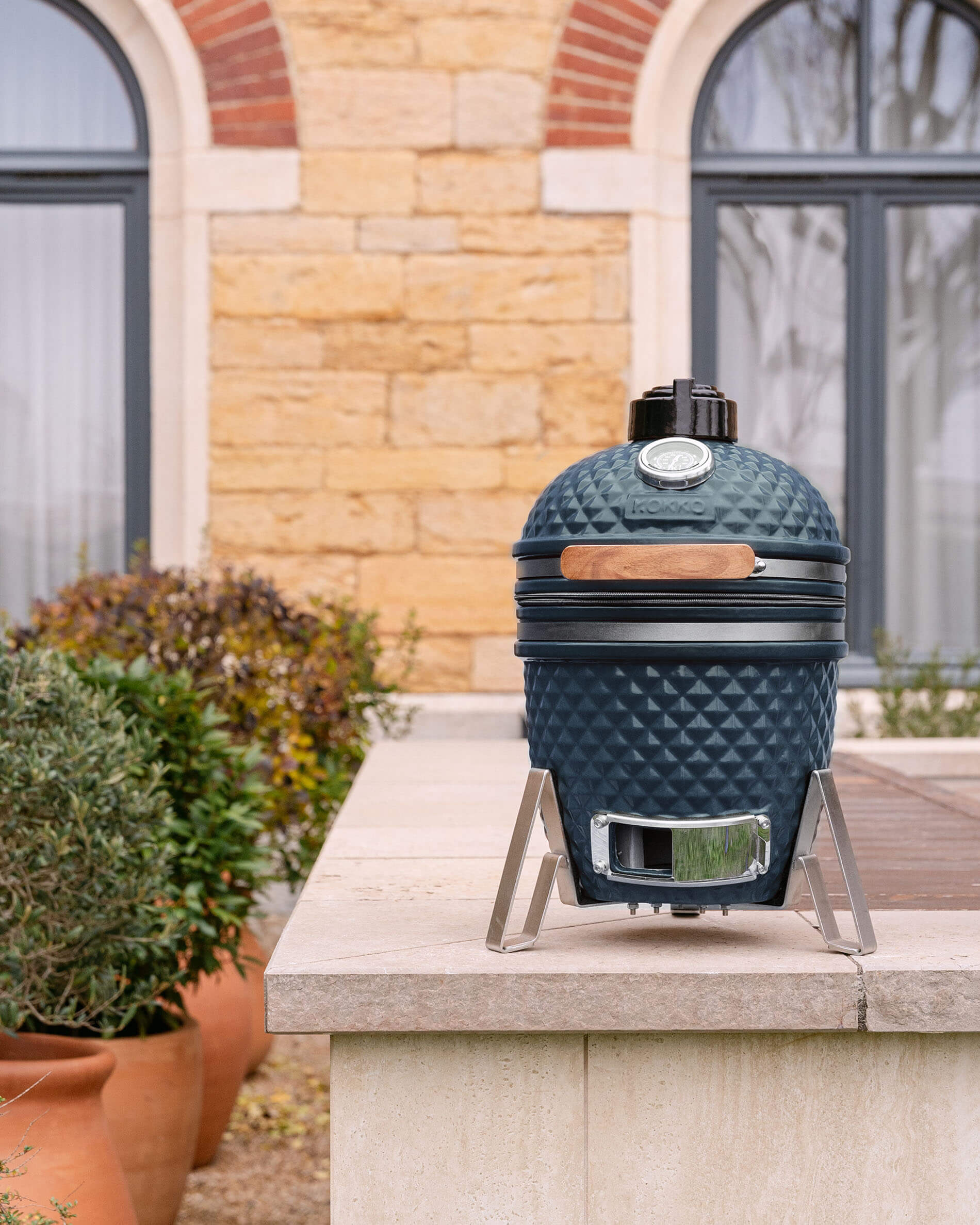 Kamado Little Kokko 13 van keramiek in oceaanblauw, geplaatst buiten.