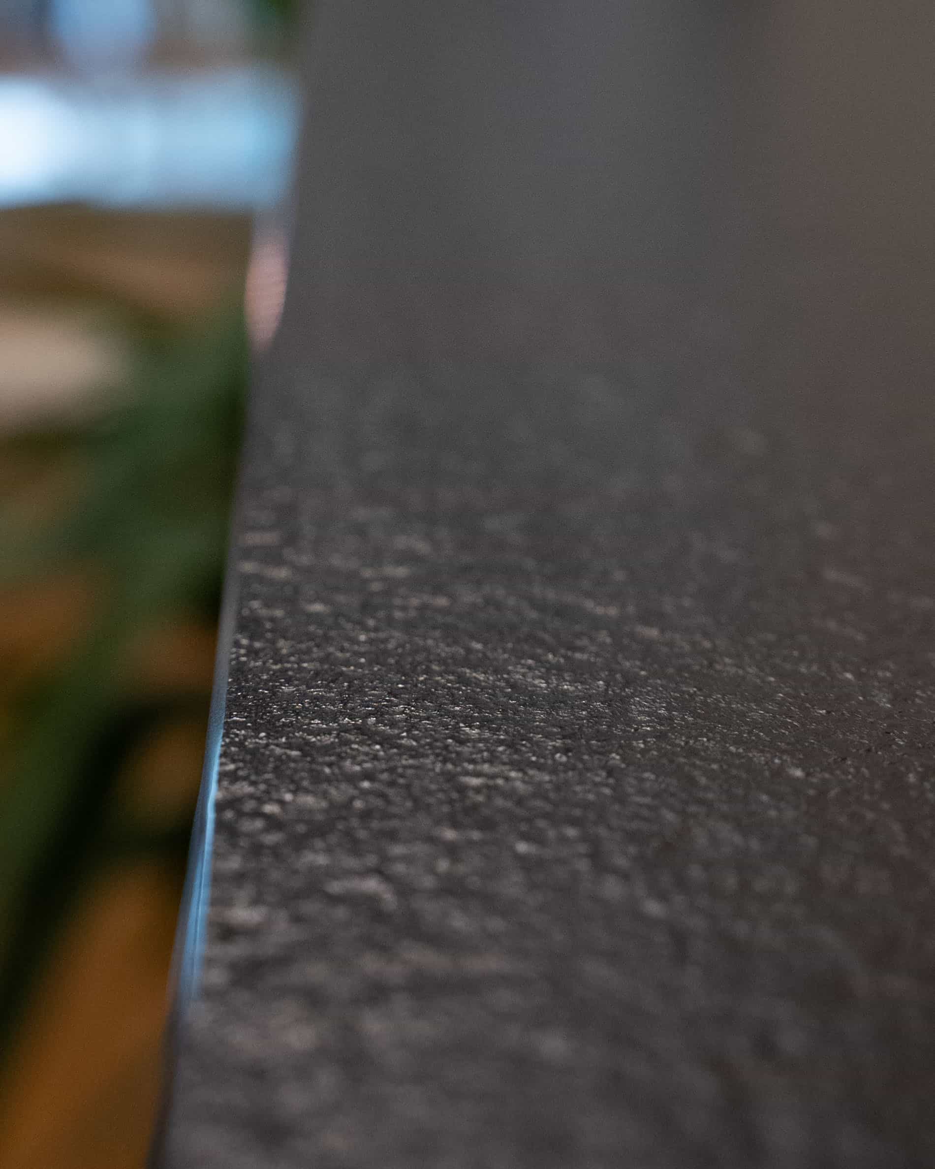 Detail van het werkblad van een paalwoning-keuken, met zicht op de rand, de matte textuur en de afwerking van het materiaal.