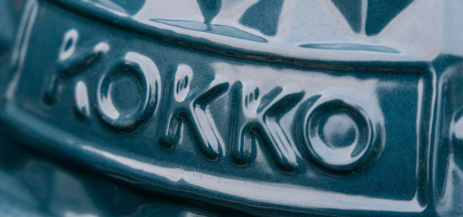 Close-up van het Kokko-logo, reliëf aangebracht in de donkergroene glanzende keramiek van de kamado.